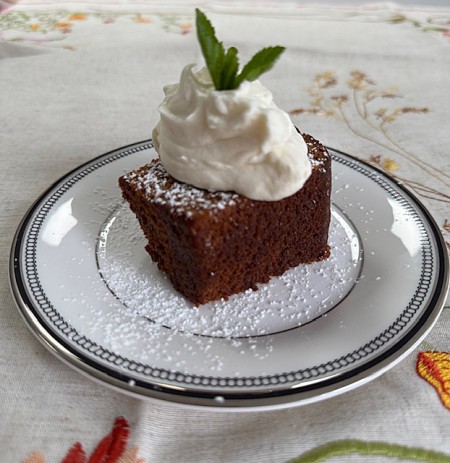 Piece of gingerbread cake topped with whipped cream