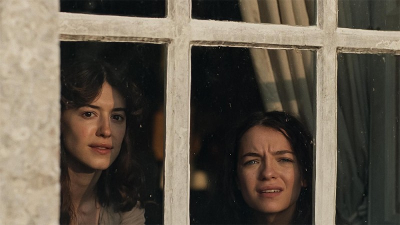 Elinor and Marianne Dashwood peer out of a window in a still photo from Focus Feature's Sense and Sensibility film.