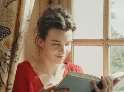 Photo still of Agathe reading a book in front of a window, from the film Jane Austen Wrecked My Life.